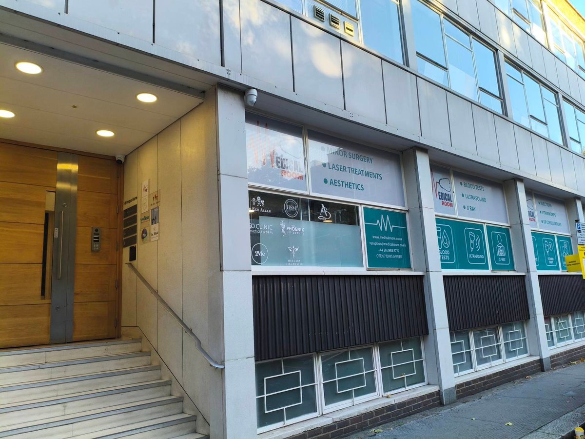 Clinic entrance at 1-5 Portpool Lane, London, featuring wooden doors, signage for medical services including ultrasound and blood tests, and steps leading to the entrance.