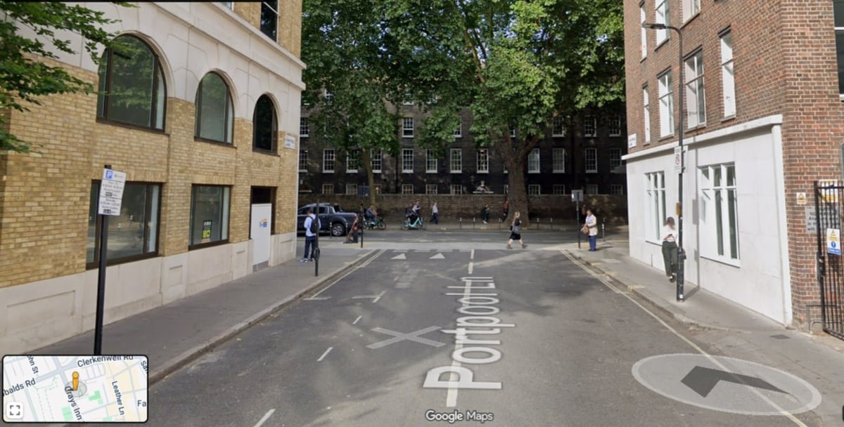 Street view of Portpool Lane near AristoGP clinic, featuring brick buildings, trees, and pedestrians, with visible signage for nearby transport options.